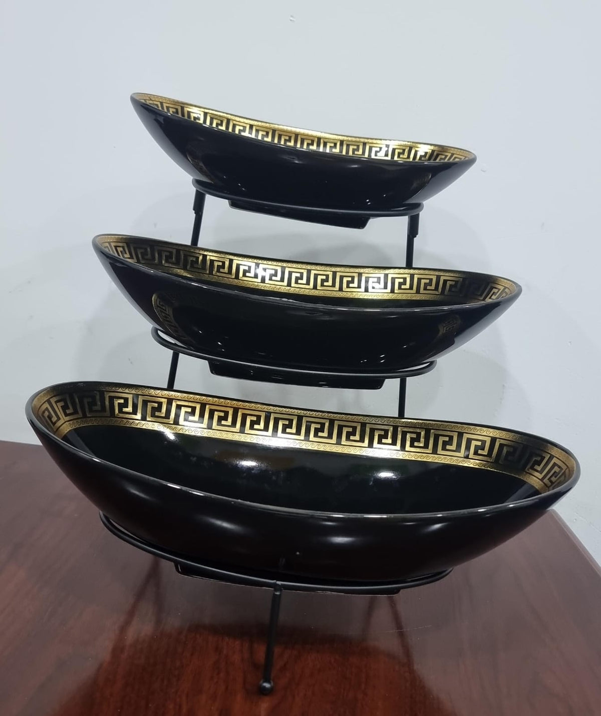 set of 3 ceramic fruit plates on black metal rack